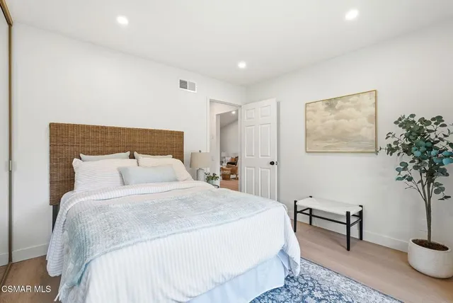 a bedroom with a large bed and a potted plant