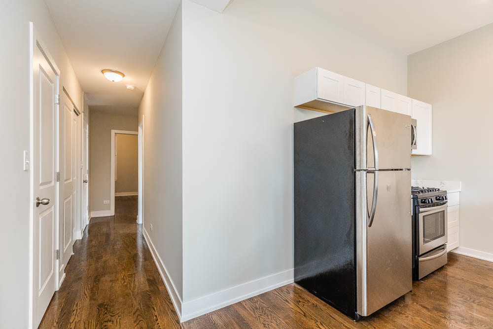 2228 West Cermak Road Chicago, IL 60608 - Photo 7 of 32 a view of a refrigerator in kitchen and an empty room with wooden floor