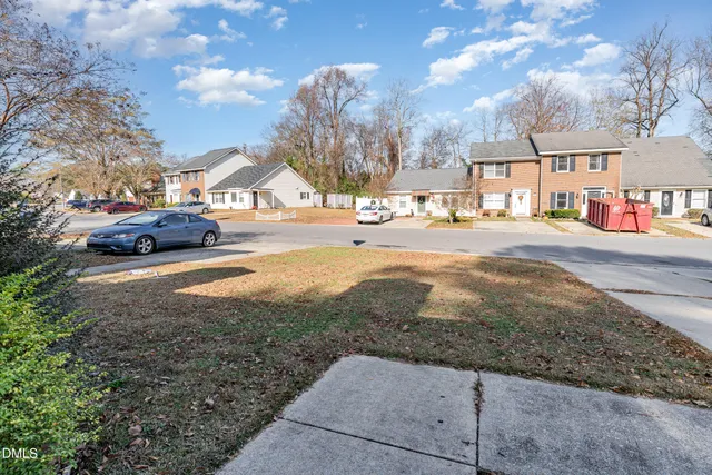 a view of a house with a small yard and a large tree