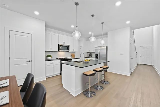 a kitchen with kitchen island a sink stainless steel appliances and white cabinets