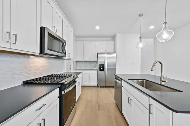 a kitchen with kitchen island a counter top space stainless steel appliances and a chandelier
