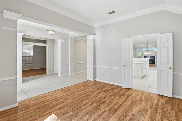 an empty room with wooden floor fireplace cabinet and windows