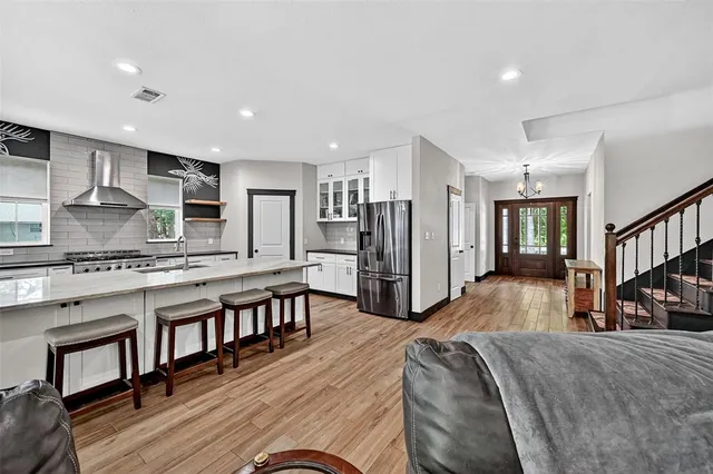 a kitchen with stainless steel appliances a dining table chairs and wooden floor