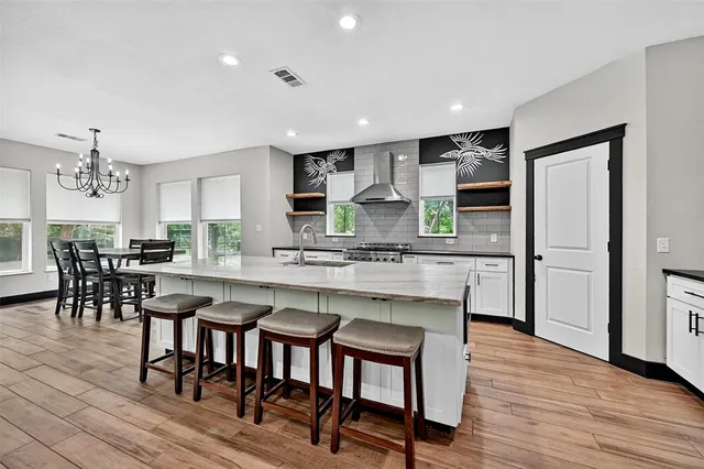 a large kitchen with stainless steel appliances granite countertop a lot of counter space and wooden floors