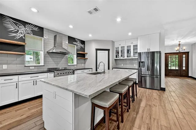 a kitchen with stainless steel appliances granite countertop a kitchen island hardwood floor sink stove and granite counter top