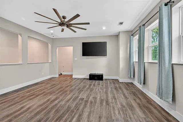 an empty room with wooden floor and windows