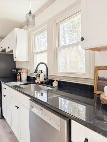 a kitchen with granite countertop a sink appliances cabinets and a large window