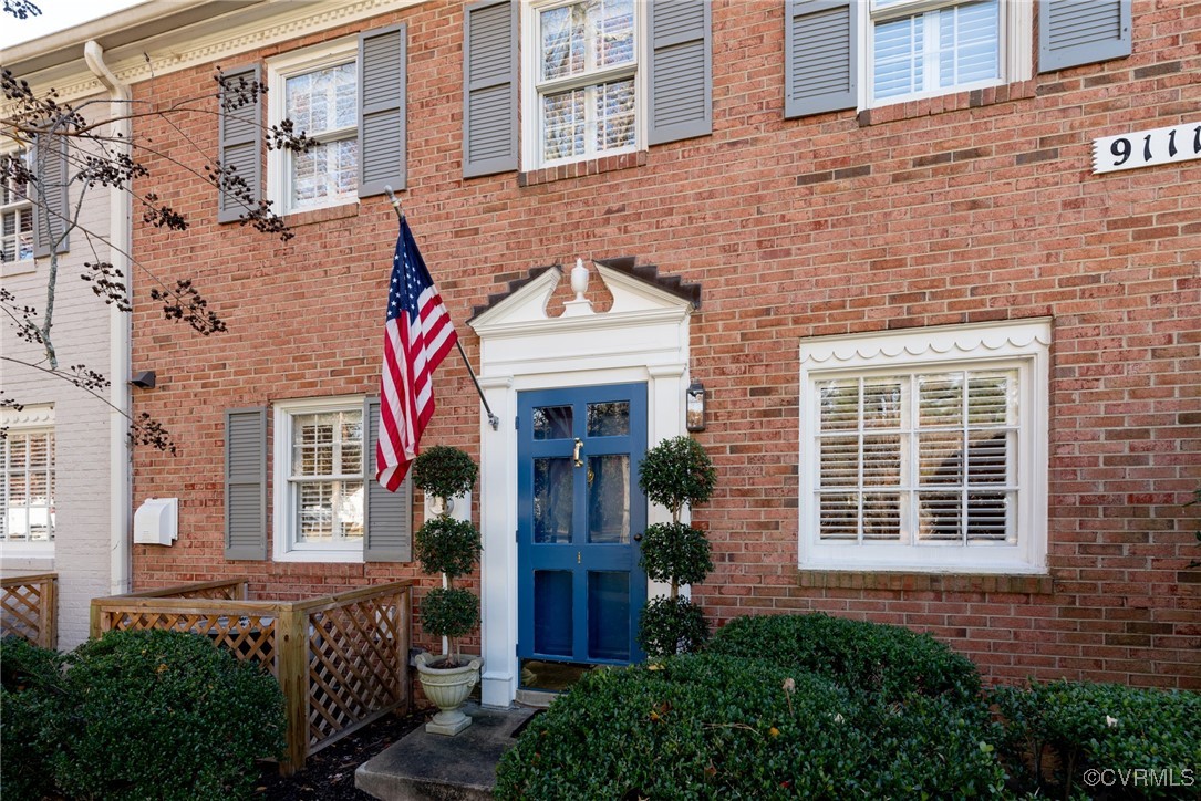9111 Derbyshire Road, Unit I Henrico, VA 23229 - Photo 2 of 22 a view of a brick house with plants and wooden fence