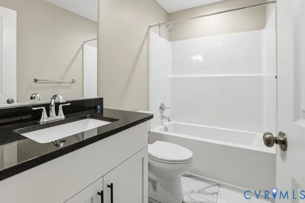 a bathroom with a granite countertop sink a toilet a mirror and shower