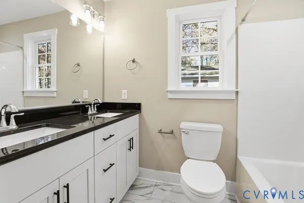 a bathroom with a granite countertop toilet sink and mirror