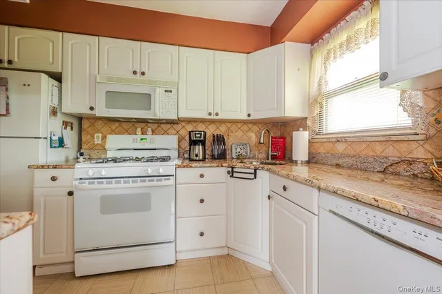 a kitchen with white cabinets and white appliances