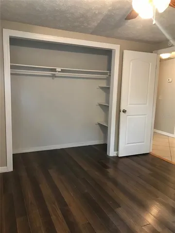 a view of an empty room with wooden floor and closet
