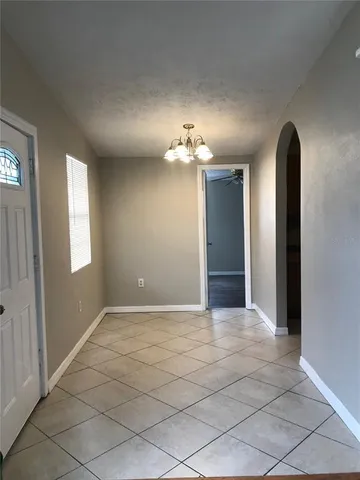 an empty room with kitchen and chandelier fan