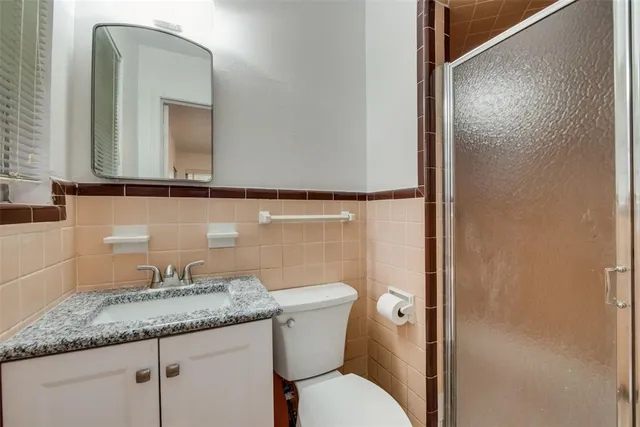 a bathroom with a granite countertop sink toilet and mirror