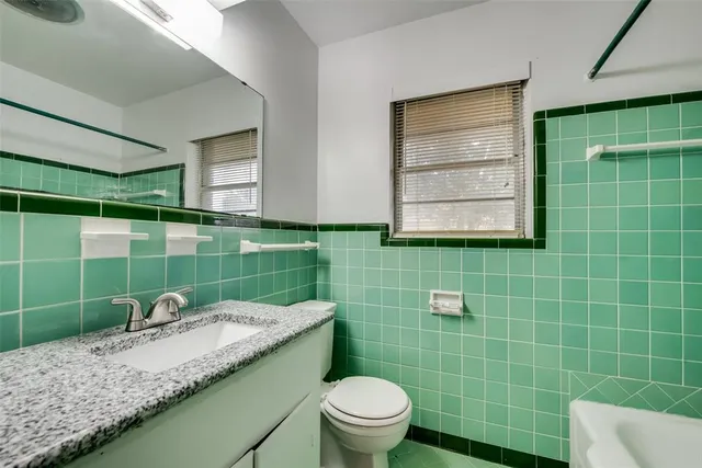 a bathroom with a granite countertop sink a toilet and mirror
