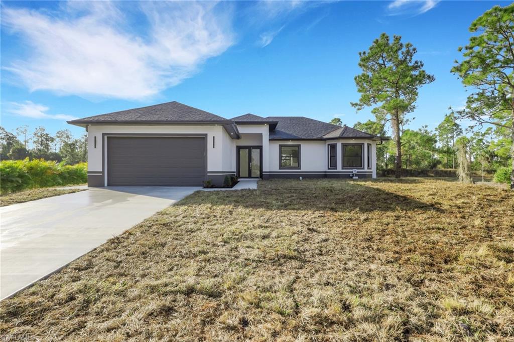 Prairie-style house featuring stucco siding, a front yard, concrete driveway, and an attached garage