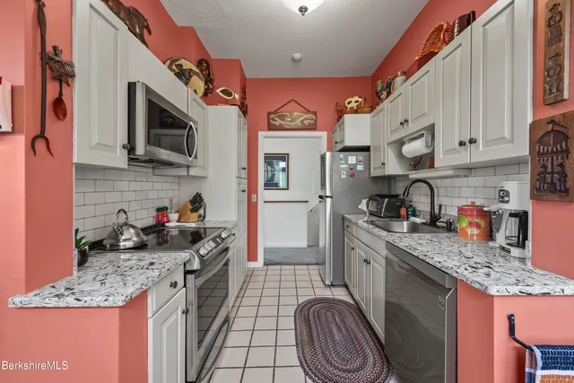 a kitchen with stainless steel appliances granite countertop a stove top oven a sink dishwasher and cabinets with wooden floor