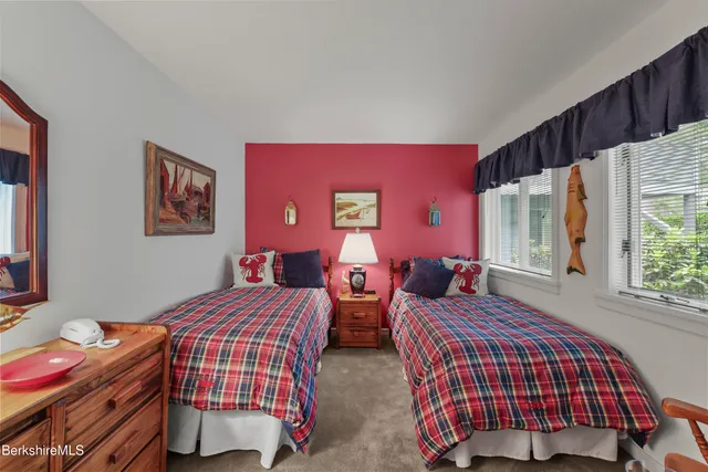 a bedroom with two beds and a dresser next to a window