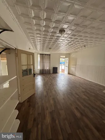 a view of an empty room with wooden floor and windows