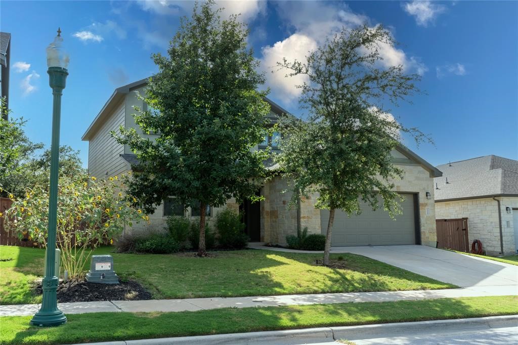 1333 Terrace View Drive Georgetown, TX 78628 - Photo 3 of 35 A welcoming stone and siding facade with a well-maintained lawn, framed by leafy green trees.