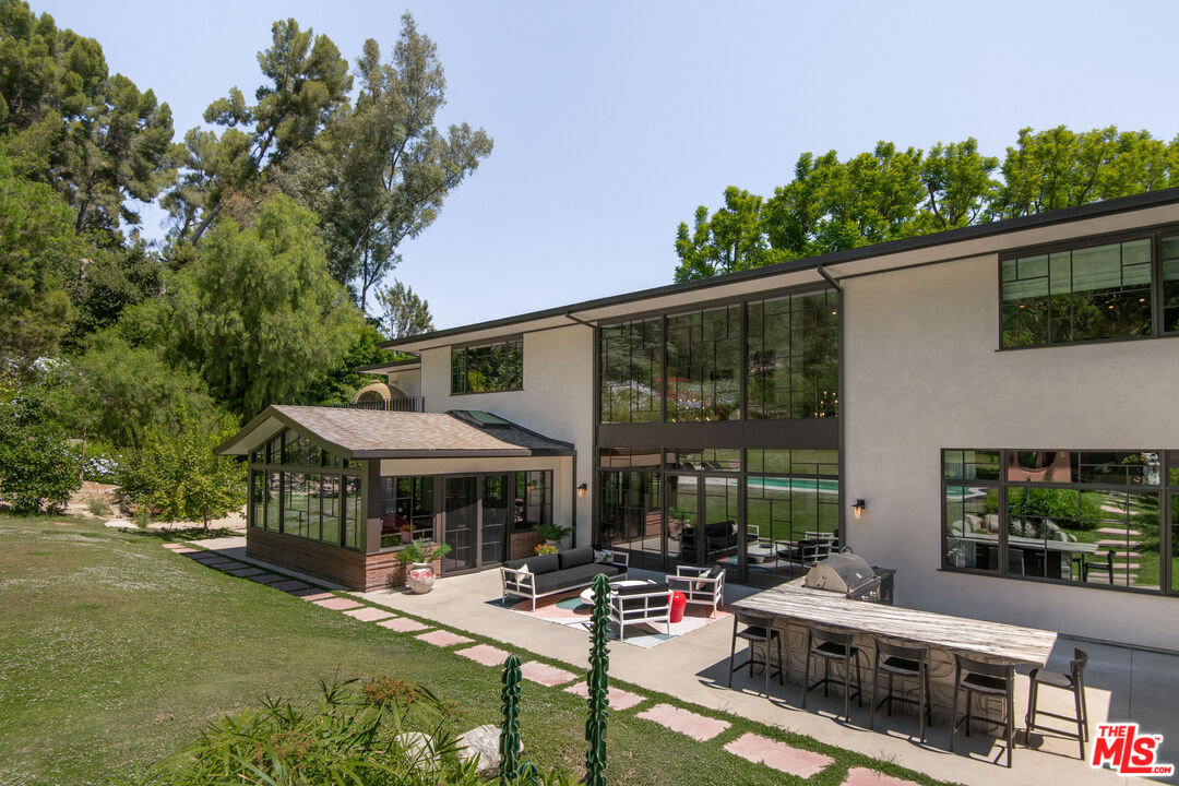 16001 Woodvale Road Encino, CA 91436 - Photo 37 of 49 a patio area with table and chairs under an umbrella