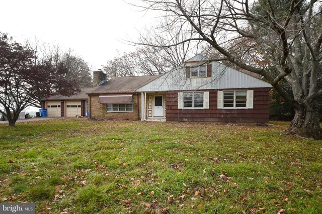 a front view of a house with a garden and trees