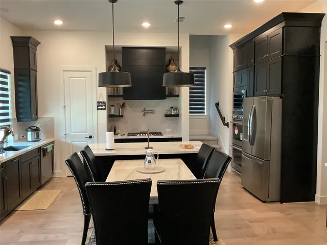 a kitchen with stainless steel appliances wooden floor dining table and chairs