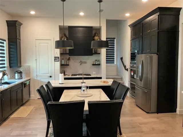 a kitchen with stainless steel appliances wooden floor dining table and chairs