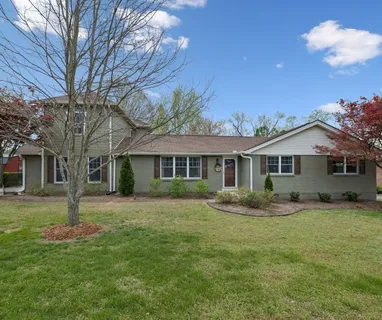 a front view of a house with a garden and trees