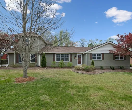 a front view of a house with a garden and trees