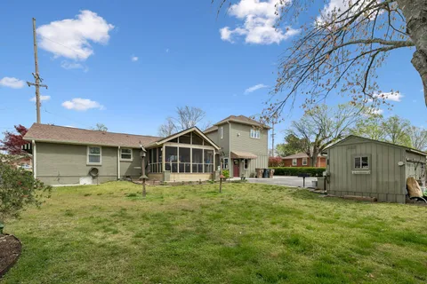 a front view of a house with a yard tree and wooden fence