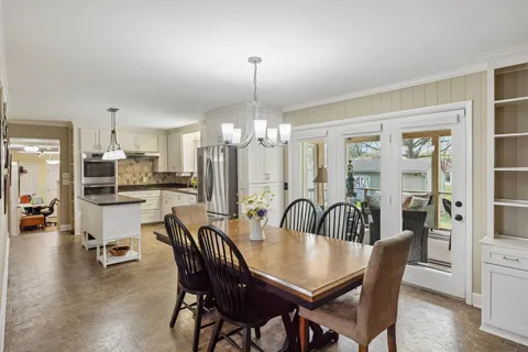 a dining room with furniture a chandelier and kitchen view