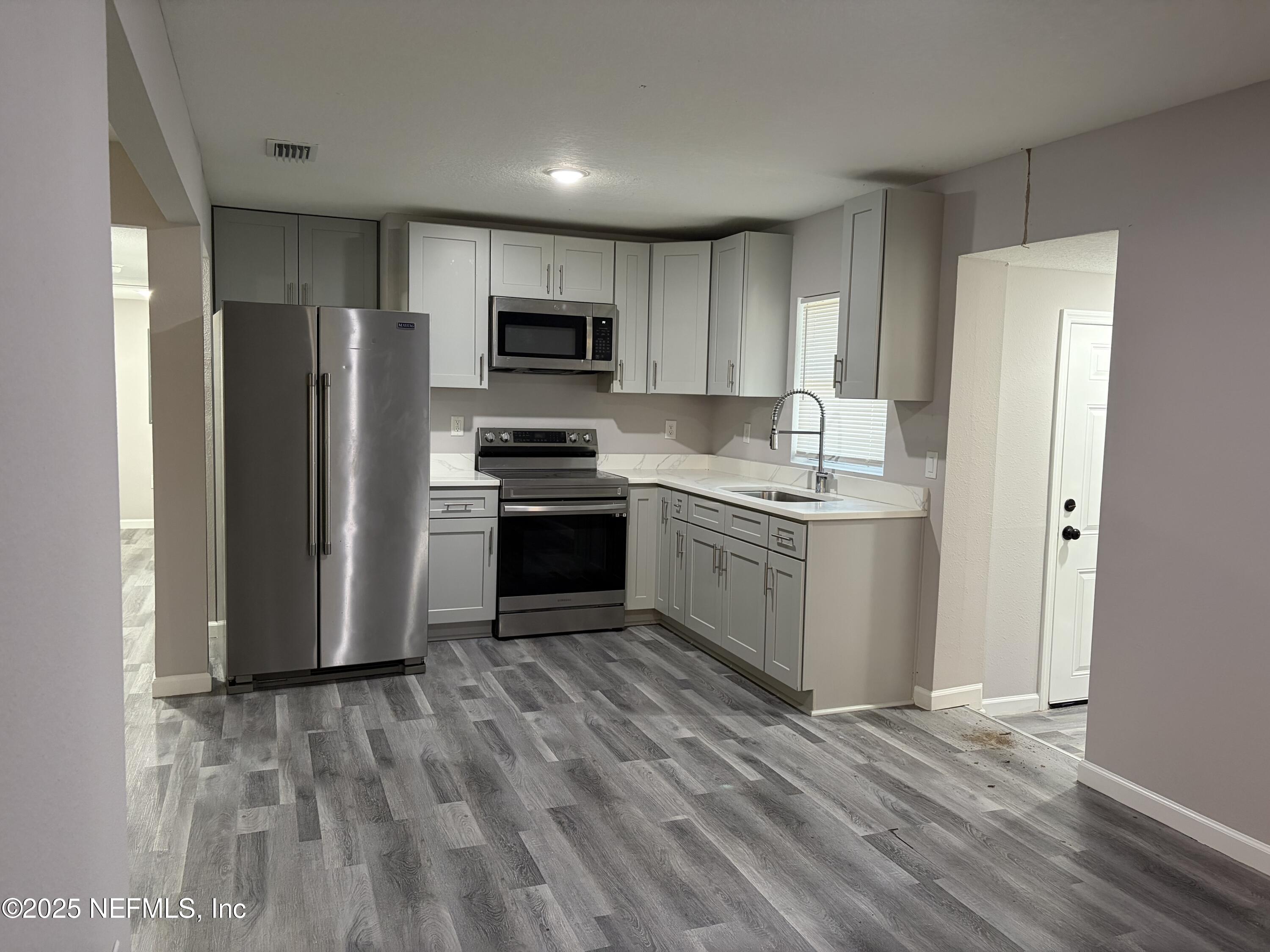 4444 Rainer Road Jacksonville, FL 32210 - Photo 4 of 19 a kitchen with stainless steel appliances granite countertop a stove top oven a refrigerator and a sink with wooden floor