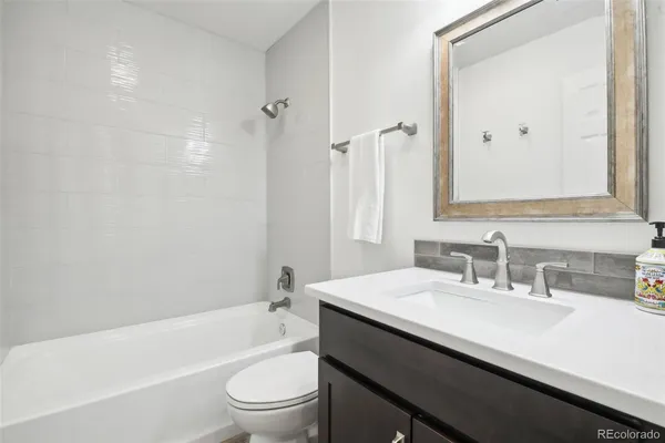 a bathroom with a sink a toilet a mirror a bathtub and shower