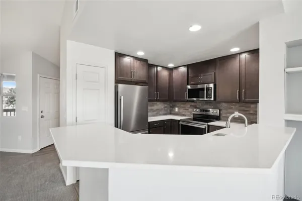 a kitchen with stainless steel appliances a refrigerator a sink a stove a microwave and island