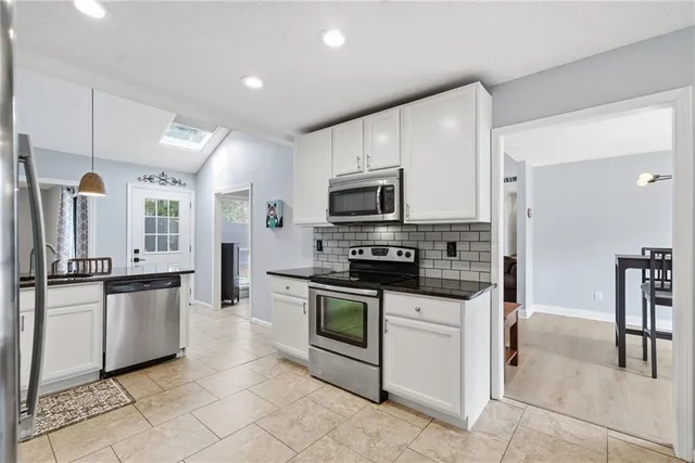 a kitchen with stainless steel appliances granite countertop a stove top oven a sink dishwasher a refrigerator and a cabinets