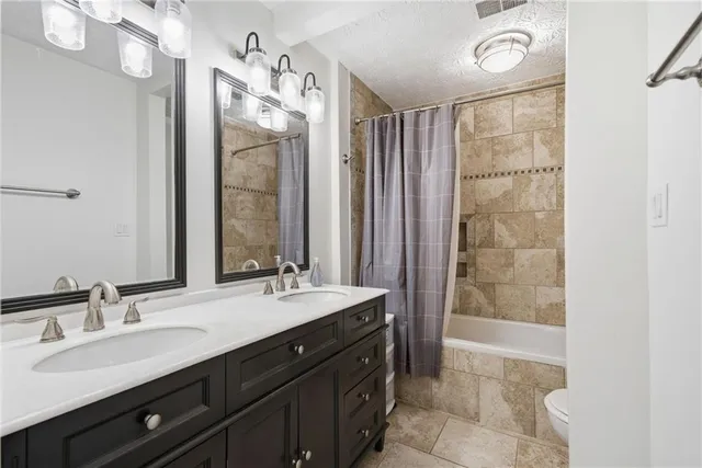 a bathroom with a double vanity sink a toilet and a mirror