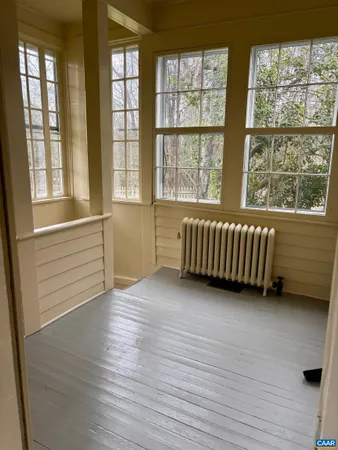 a view of an empty room with wooden floor and windows