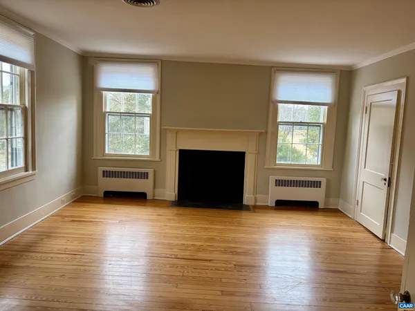 an empty room with windows and fireplace