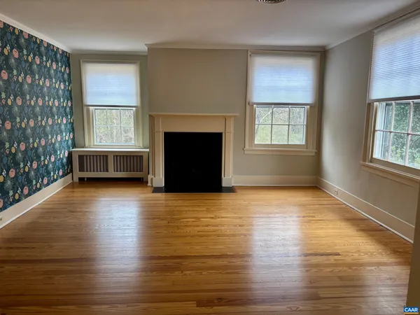 a view of an empty room with window and wooden floor