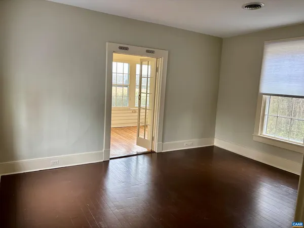 a view of an empty room with wooden floor and a window