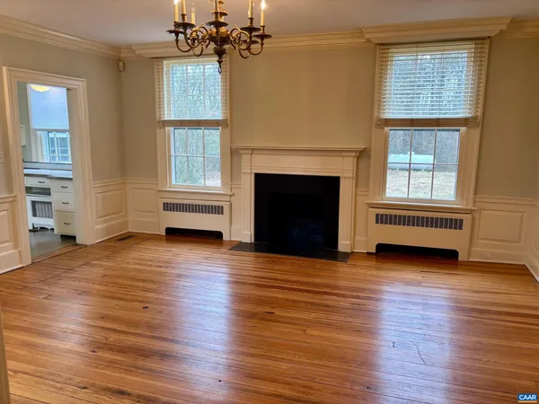 an empty room with wooden floor fireplace and windows