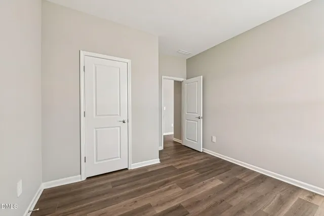 a view of an empty room with wooden floor and closet
