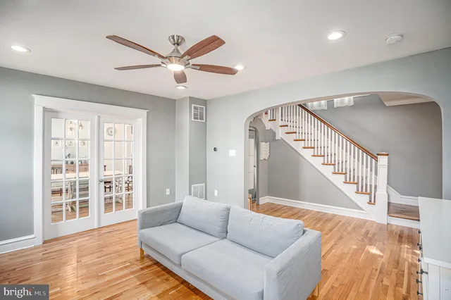 a living room with wooden floor and a ceiling fan