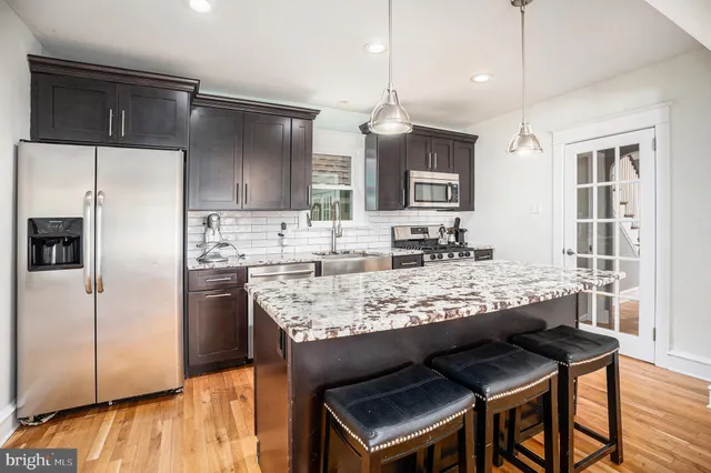 a kitchen with granite countertop kitchen island stainless steel appliances a sink and refrigerator