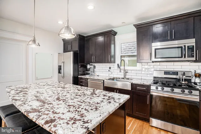 a kitchen with stainless steel appliances kitchen island granite countertop a stove refrigerator and cabinets