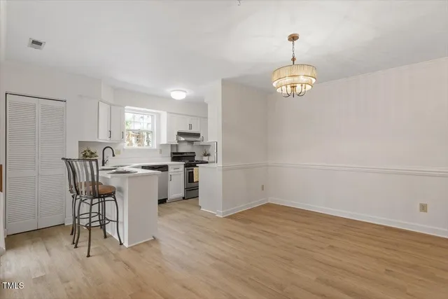 a view of a dining room with furniture a chandelier and wooden floor