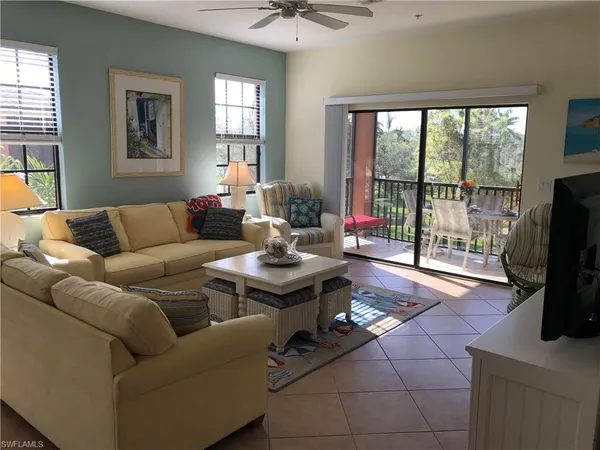 a living room with furniture a flat screen tv and a floor to ceiling window