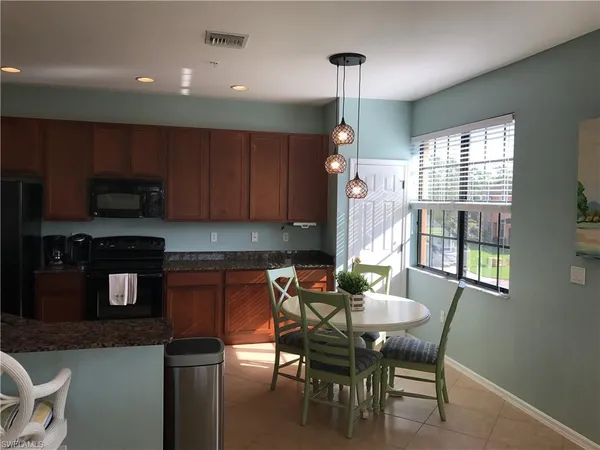 a kitchen with a dining table chairs and a refrigerator