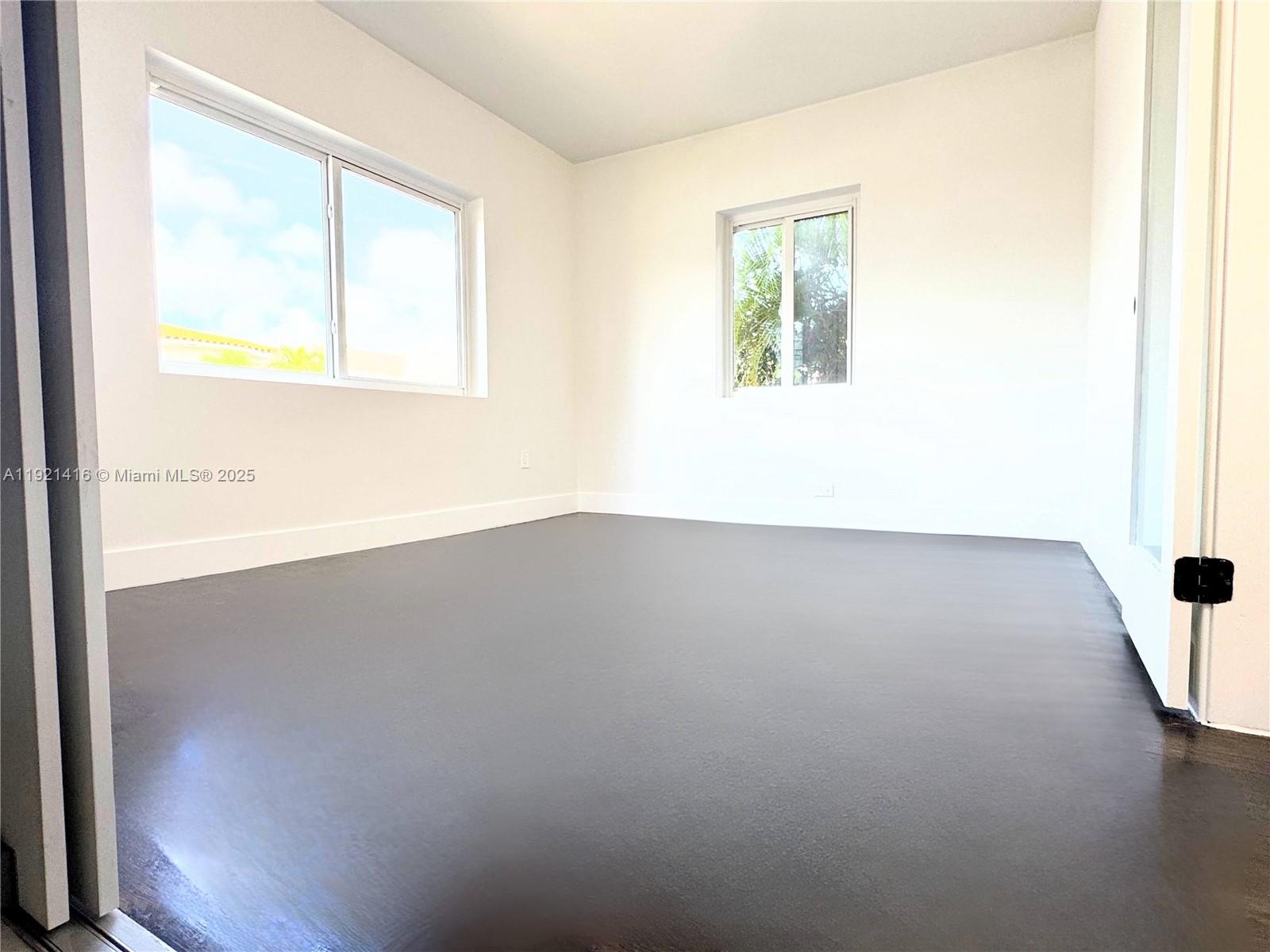 7325 Byron Avenue, Unit 8 Miami Beach, FL 33141 - Photo 2 of 16 an empty room with wooden floor and windows